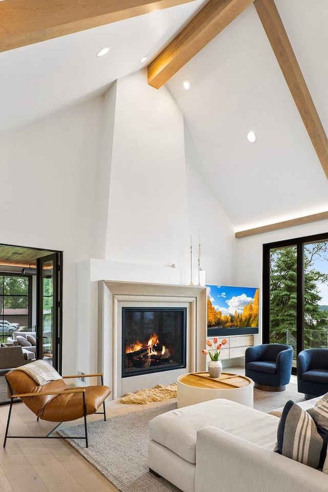 living room with a healthy amount of sunlight, high vaulted ceiling, light hardwood / wood-style floors, and beamed ceiling