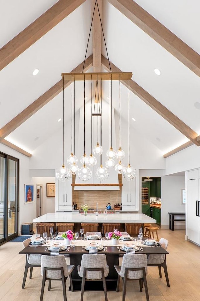 dining room with high vaulted ceiling, light hardwood / wood-style floors, and beamed ceiling