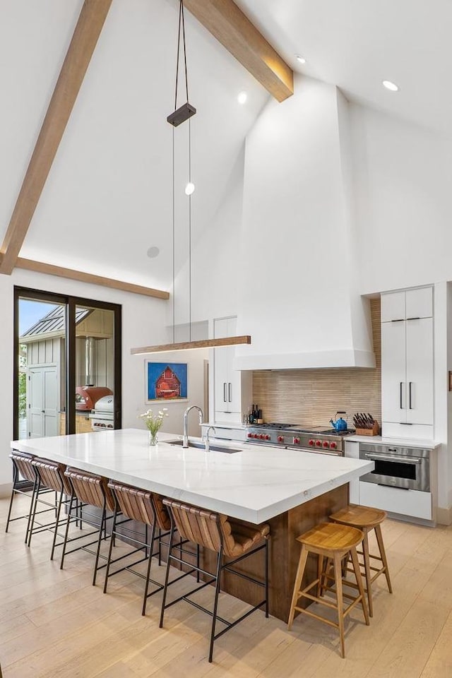 kitchen with a large island with sink, sink, pendant lighting, and a breakfast bar