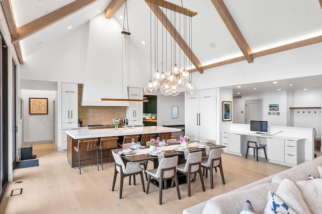 dining area with beamed ceiling, built in desk, and light wood-type flooring