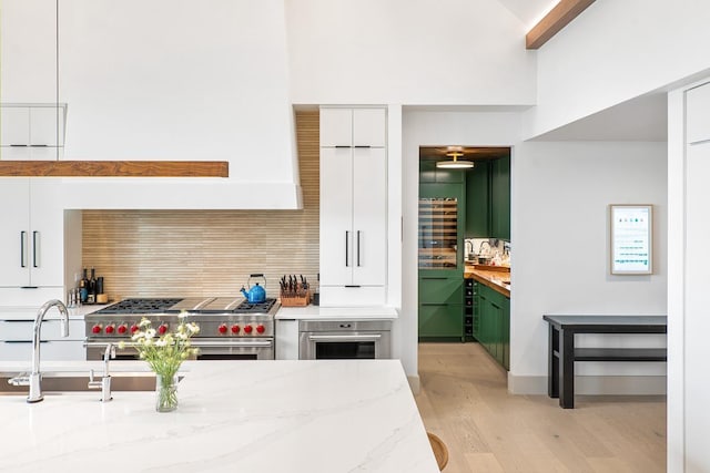 kitchen with white cabinetry, tasteful backsplash, light stone countertops, and appliances with stainless steel finishes