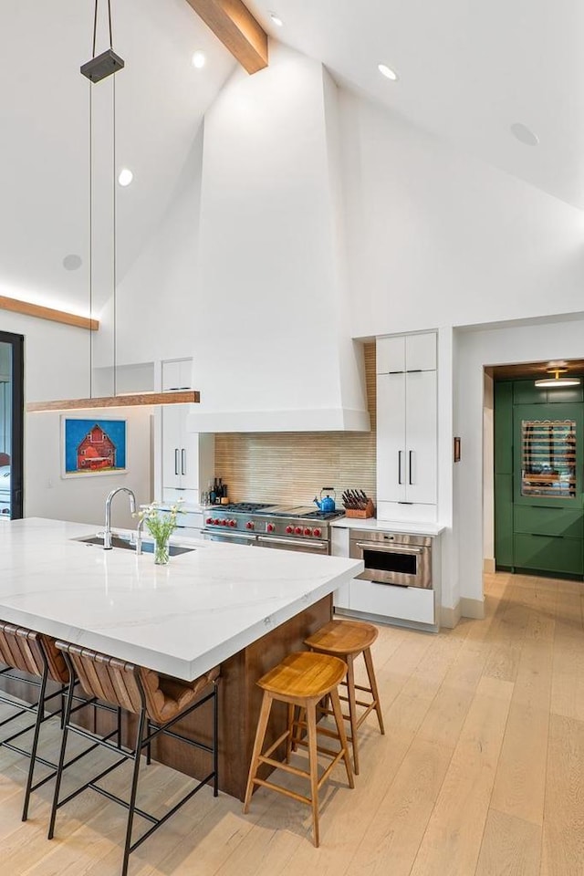 kitchen with pendant lighting, a kitchen breakfast bar, sink, and white cabinets