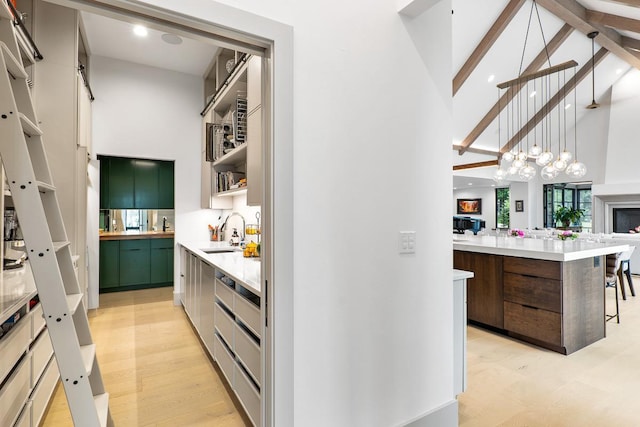 kitchen with sink, decorative light fixtures, high vaulted ceiling, light hardwood / wood-style flooring, and a kitchen island