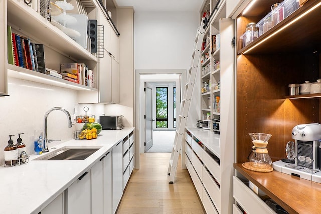 kitchen featuring sink, white cabinets, and light wood-type flooring