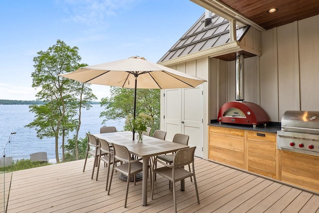 wooden terrace with a grill, exterior kitchen, and a water view