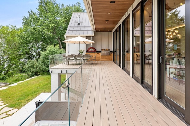 deck featuring a grill, a lawn, and exterior kitchen