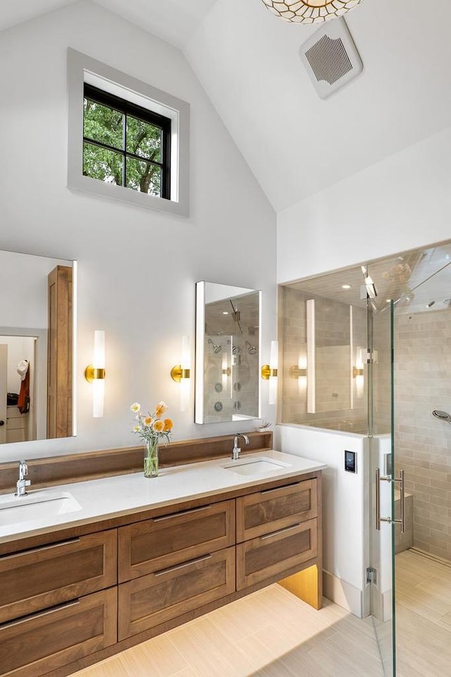 bathroom with vanity, high vaulted ceiling, and a shower with door