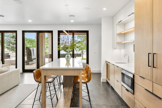 kitchen featuring a healthy amount of sunlight, sink, light brown cabinets, and a kitchen bar