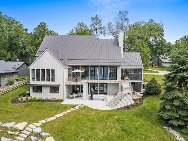 rear view of property featuring a patio, a sunroom, and a lawn