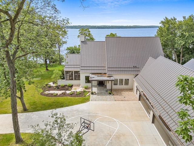 exterior space with basketball court, a front yard, and a water view