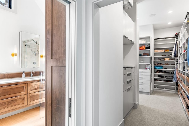 walk in closet with light colored carpet and sink