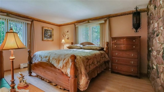 bedroom featuring a baseboard heating unit and light hardwood / wood-style flooring