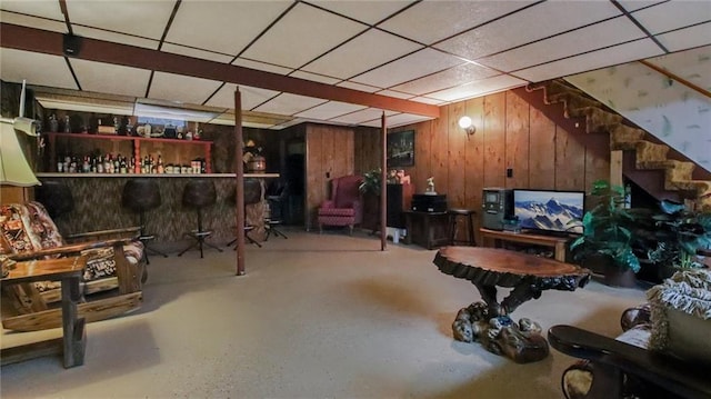 basement with wood walls and a drop ceiling