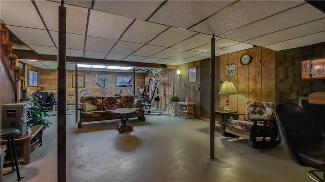 basement featuring a paneled ceiling and wood walls