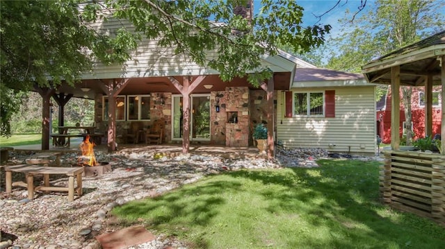 rear view of house with a fire pit, a patio area, and a lawn