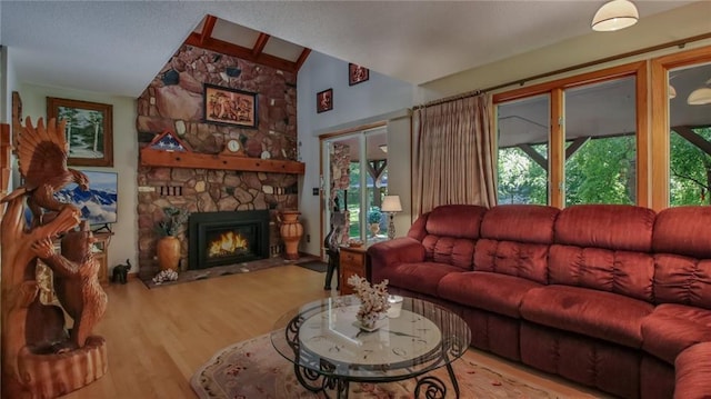 living room featuring hardwood / wood-style floors, a stone fireplace, and lofted ceiling