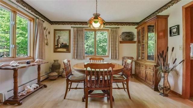 dining space with light wood-type flooring, a wealth of natural light, and a baseboard heating unit