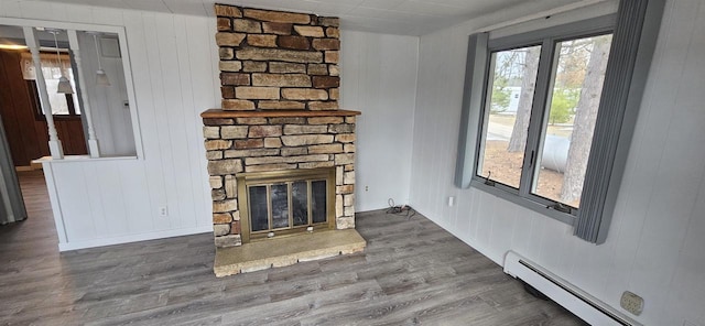 N9451 Parkway Rd, Crivitz, WI 54114 - unfurnished living room featuring a baseboard radiator, a stone fireplace, wood finished floors, and wooden walls