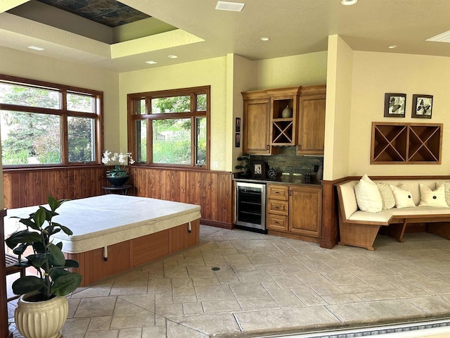 kitchen with decorative backsplash, wood walls, and beverage cooler