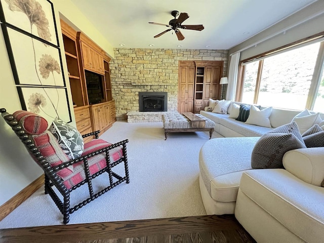 living room featuring a stone fireplace and ceiling fan