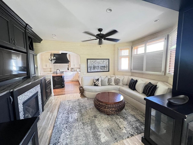 living room featuring ceiling fan with notable chandelier, light hardwood / wood-style floors, and sink