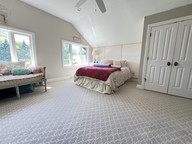 carpeted bedroom with multiple windows, a closet, vaulted ceiling, and ceiling fan