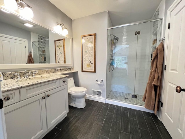 bathroom with walk in shower, vanity, and toilet