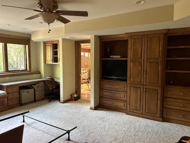 living room featuring ceiling fan, light colored carpet, and built in desk