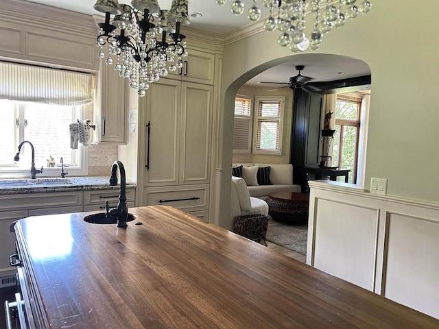 dining space with hardwood / wood-style flooring, ceiling fan with notable chandelier, ornamental molding, and sink