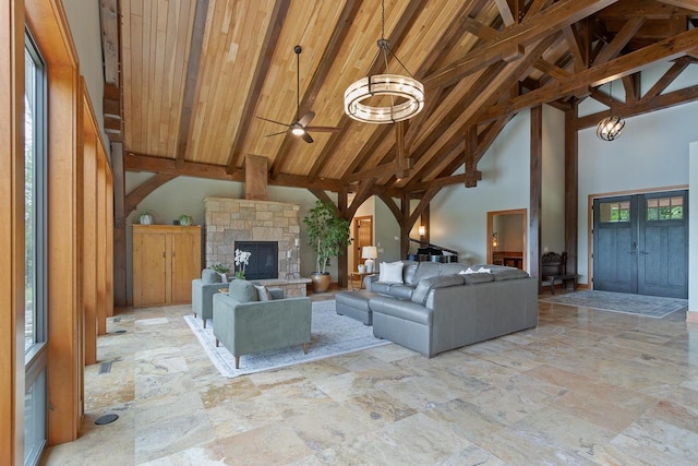 unfurnished living room featuring beamed ceiling, ceiling fan with notable chandelier, a healthy amount of sunlight, and high vaulted ceiling