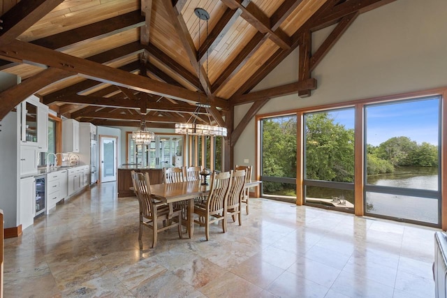 unfurnished dining area with a water view, high vaulted ceiling, an inviting chandelier, beamed ceiling, and wine cooler