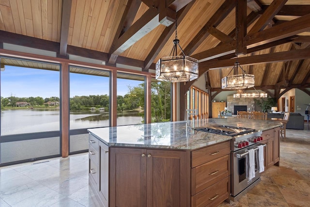 kitchen featuring pendant lighting, a center island with sink, a water view, designer stove, and light stone counters