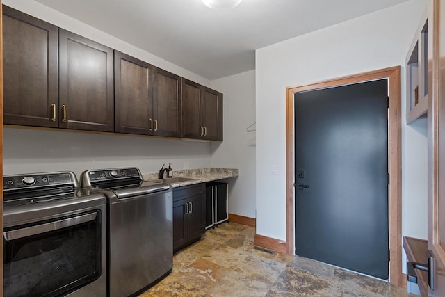 clothes washing area with cabinets, washer and dryer, and sink