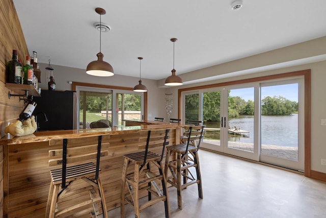 kitchen with black refrigerator, decorative light fixtures, a water view, and french doors