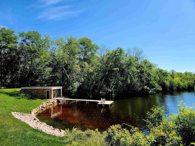 view of community featuring a water view, a dock, and a lawn