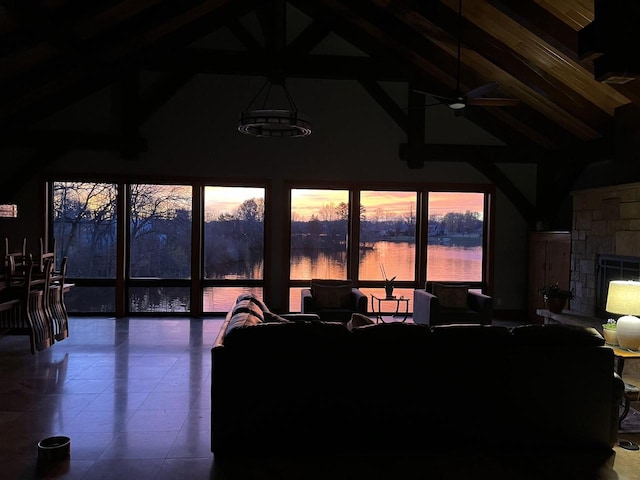 tiled living room with high vaulted ceiling, a water view, ceiling fan, a fireplace, and beam ceiling