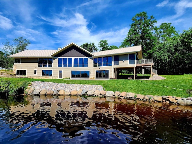 back of house featuring a deck with water view and a yard