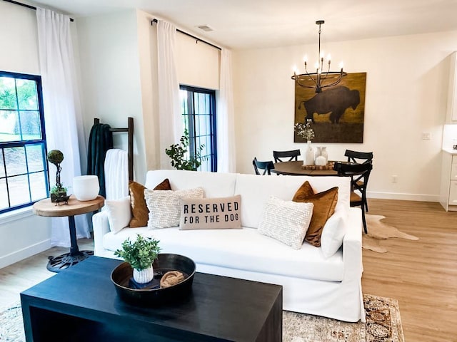 living room with light hardwood / wood-style floors and an inviting chandelier