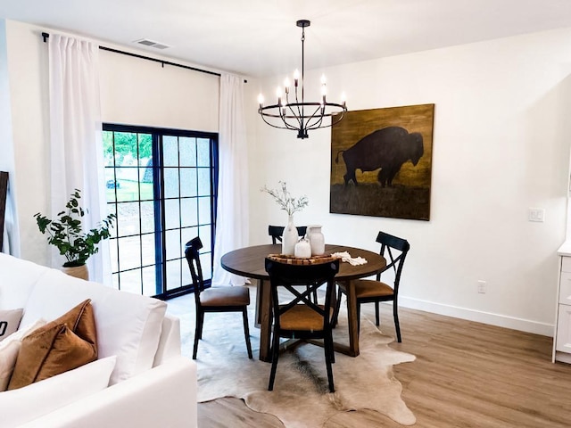 dining area with light hardwood / wood-style floors and an inviting chandelier