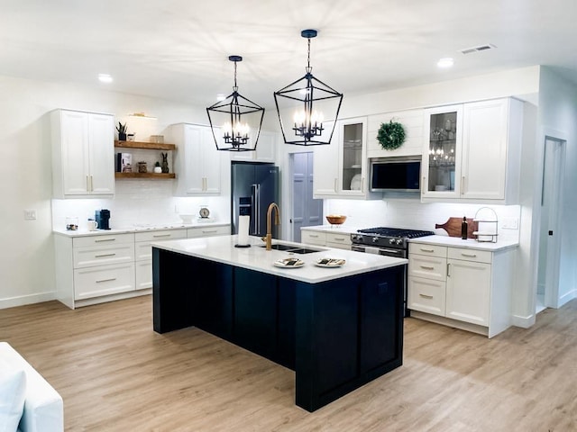 kitchen with a kitchen island with sink, white cabinets, sink, high quality fridge, and light hardwood / wood-style floors