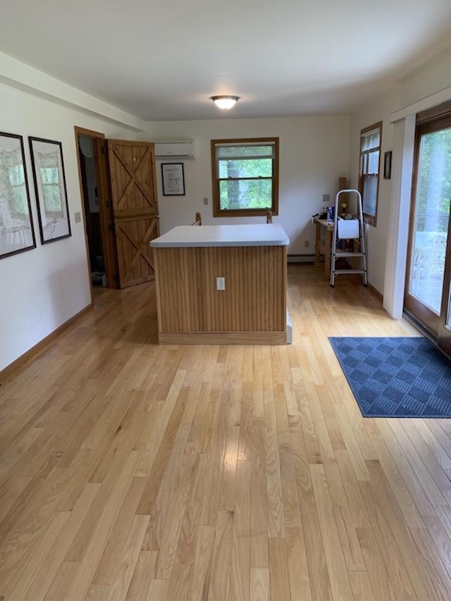 kitchen featuring a center island, a barn door, light hardwood / wood-style flooring, and a wall mounted AC