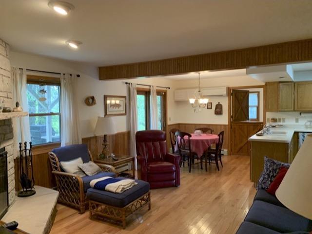 living room featuring sink, a wall unit AC, a chandelier, light hardwood / wood-style floors, and a fireplace