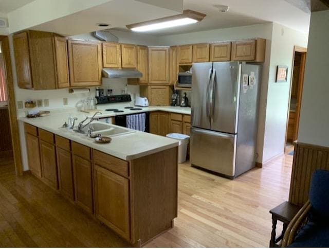 kitchen featuring kitchen peninsula, sink, light wood-type flooring, and appliances with stainless steel finishes