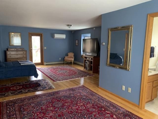 bedroom featuring ensuite bath, light hardwood / wood-style floors, and a wall mounted air conditioner