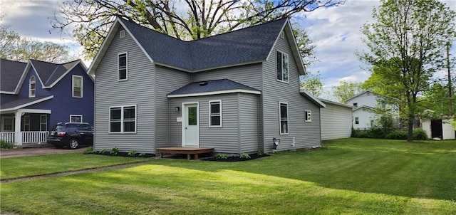 back of property with a lawn and roof with shingles