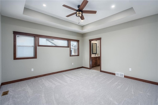 carpeted spare room featuring ceiling fan and a tray ceiling