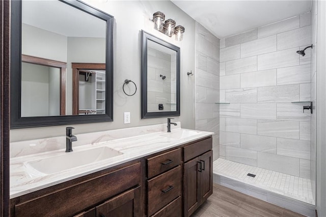 bathroom with a tile shower, vanity, and hardwood / wood-style flooring