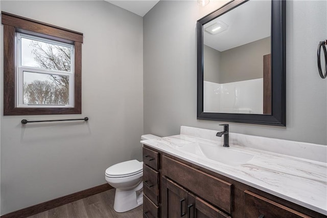 bathroom with a shower, vanity, hardwood / wood-style flooring, and toilet