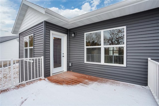 snow covered property entrance featuring a wooden deck