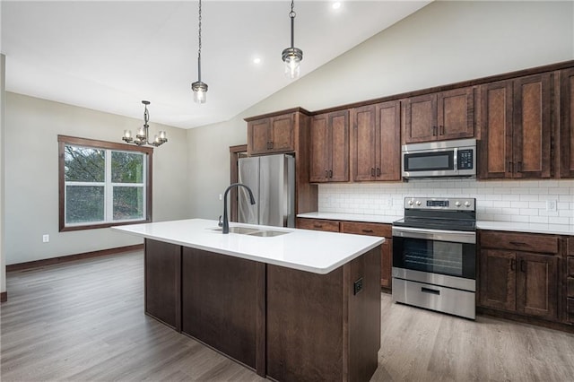 kitchen with a notable chandelier, sink, a kitchen island with sink, and appliances with stainless steel finishes